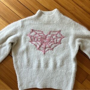 White sweater with spiderweb-heart design